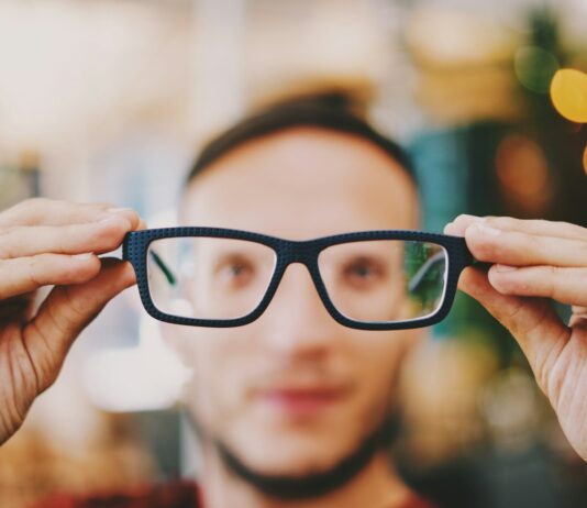 스마트 시대, 눈 건강 지키는 방법은? 디지털 기기 사용과 올바른 관리법 person holding eyeglasses with black frames