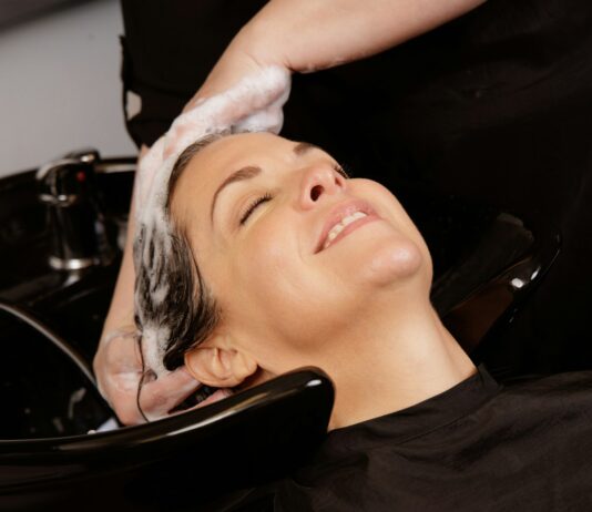 “두피 관리부터 ‘저자극 펩타이드’까지, 건강한 헤어 트렌드 총정리” A woman enjoys a hair wash at a salon.