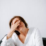 “만성피로, 단순한 피곤함 넘어서 — 최신 연구와 트렌드로 바라본 똑똑한 관리법” a woman sitting on a couch holding her hands to her face
