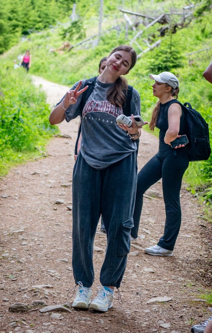Young woman makes peace sign on a forest trail